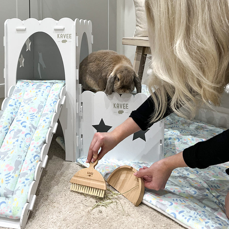 blonde person using kavee dustpan and brush to sweep up hay off floor